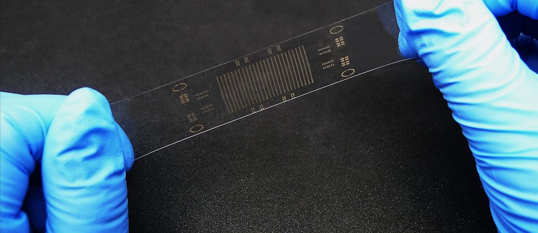 Intrinsically stretchable printed circuit being stretched by gloved hands in the LiDM lab
